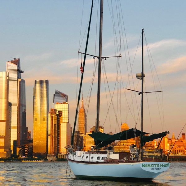a large ship in a body of water with a city in the background