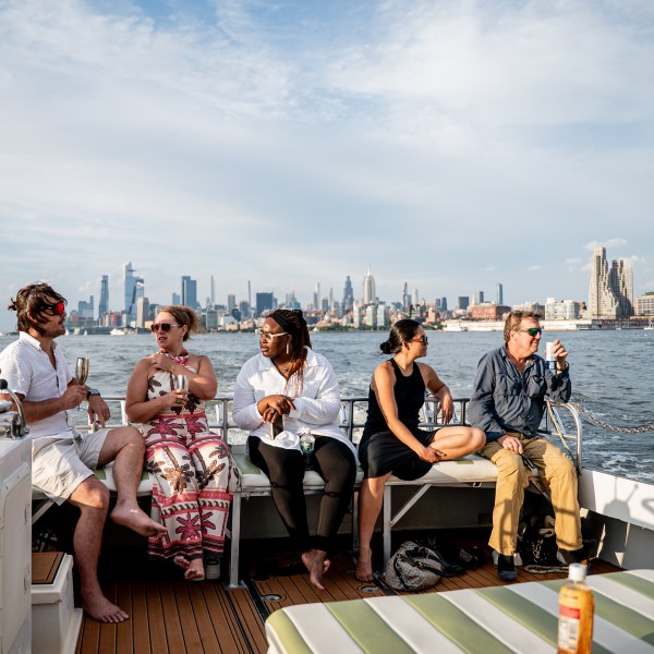 People sitting on a boat deck with a city skyline in the background.