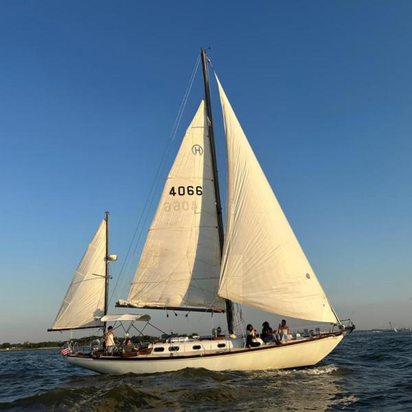 Sailboat with white sails on calm water under clear blue sky.