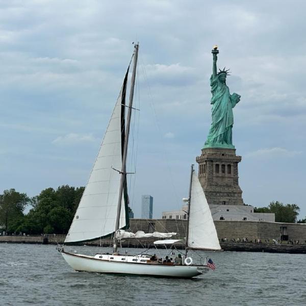 Sailboat near the Statue of Liberty on a cloudy day.