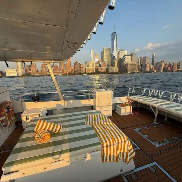 Boat deck with striped towels, city skyline and One World Trade Center in background.
